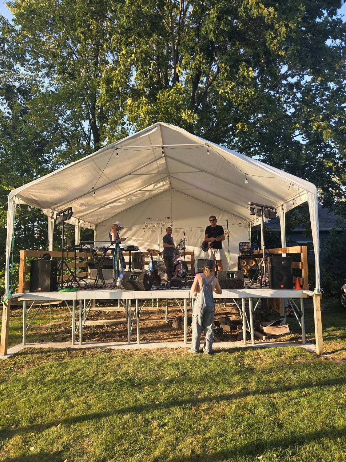 A band playing on the covered stage on the lawn