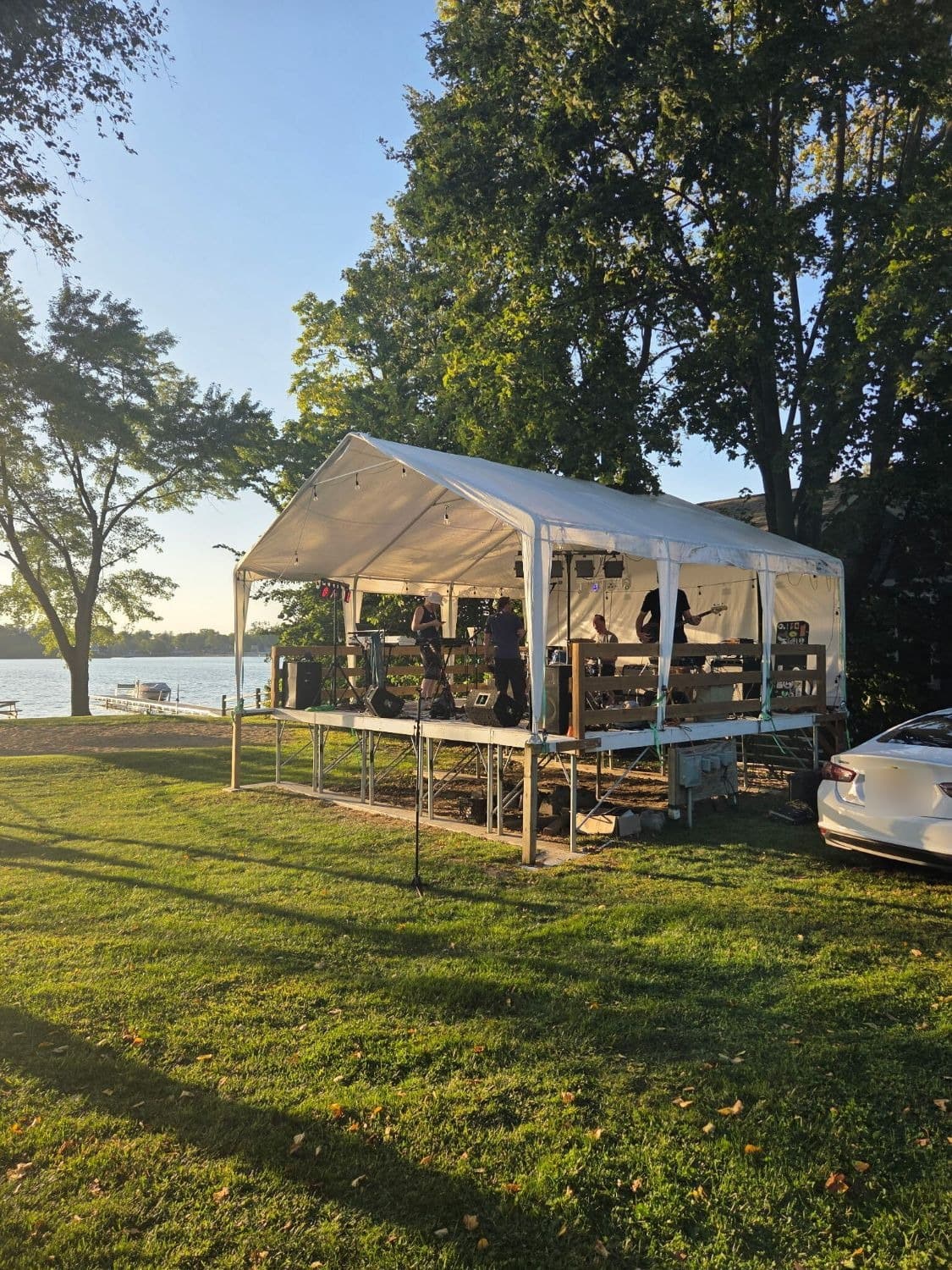 A band on the covered lawn stage with Lily Lake behind it at sunset